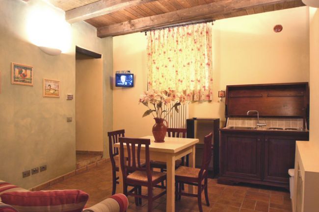 Soggiorno con tavolo, sedie e piccolo angolo cottura.