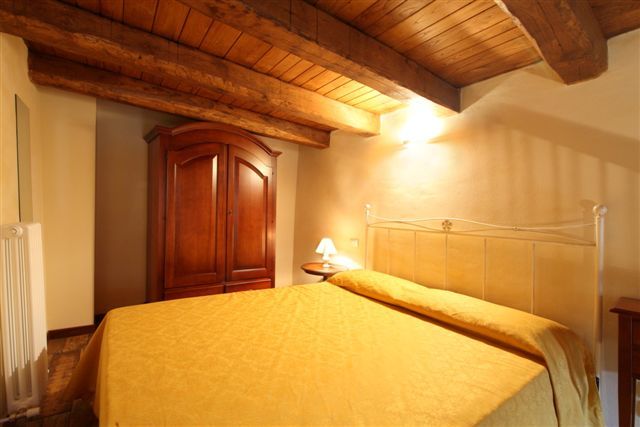 Una camera con letto matrimoniale e travi in legno a vista.