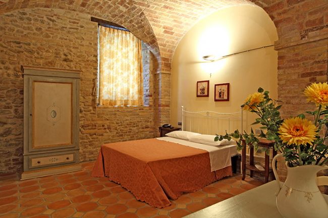 Camera da letto con pareti di mattoni e fiori sul tavolo.
