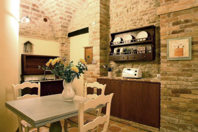 Cucina con tavolo, sedie e pareti in mattoni.