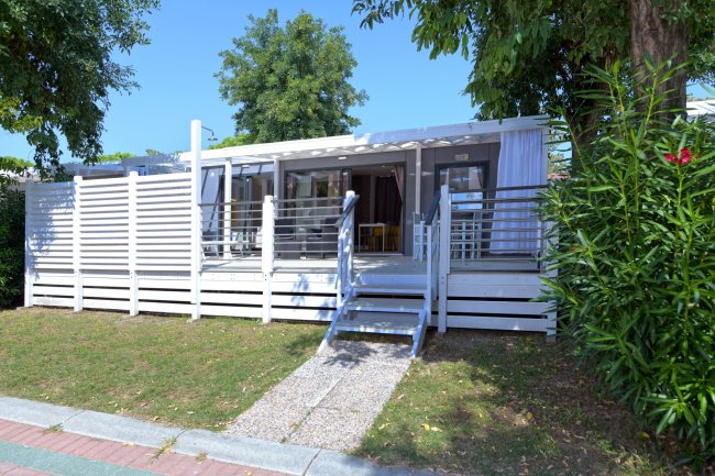 Veranda di una casa mobile circondata dal verde.