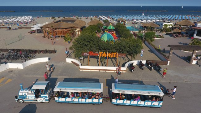 Trenino turistico davanti a uno stabilimento balneare.