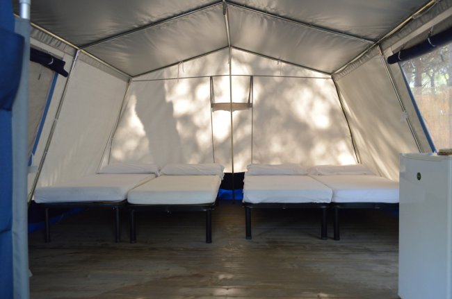 Interno di una tenda con quattro letti singoli allineati.
