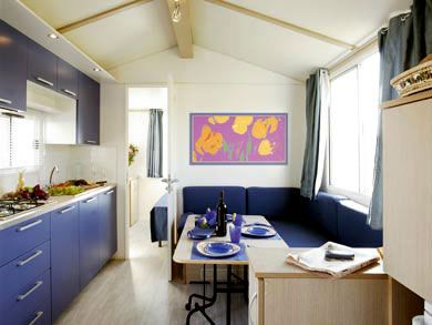 Cucina moderna con mobili blu, tavolo apparecchiato e divano ad angolo.