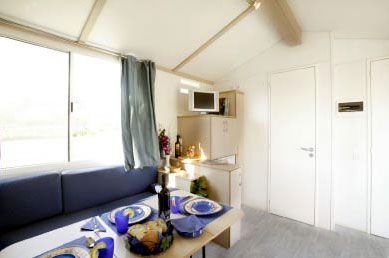 Soggiorno con divano blu, tavolo apparecchiato e una piccola area cucina con microonde.