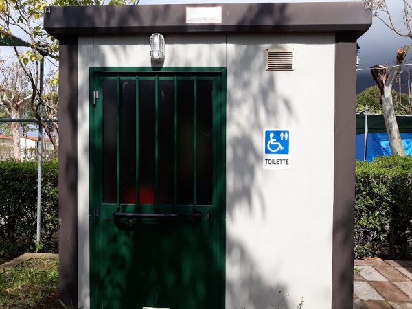 Toilette accessibile con porta verde e segnaletica per disabili.