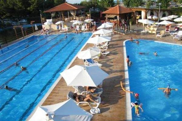 Due piscine affiancate con persone che nuotano e si rilassano sotto gli ombrelloni.