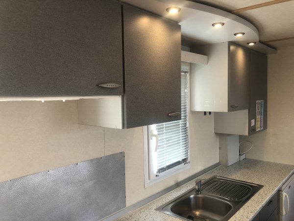 Cucina moderna con pensili grigi, lavabo in acciaio e una finestra.