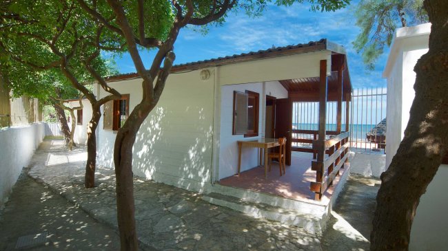 Una veranda di una casa bianca con tettoia in legno vista mare.