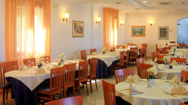 Ristorante elegante con tavoli apparecchiati, sedie in legno e tende arancioni.