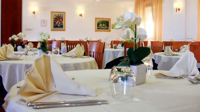 Ristorante con tavoli apparecchiati e decorazioni floreali.
