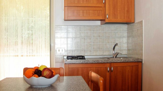 Una cucina con mobili in legno e un tavolo con un cesto di frutta.