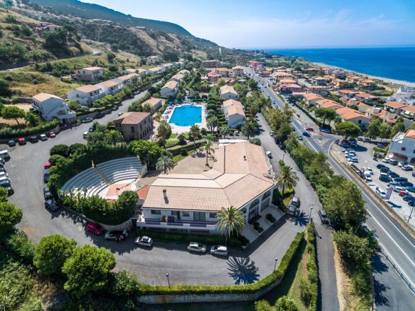 Vista aerea su un complesso turistico con piscina e anfiteatro vicino al mare.