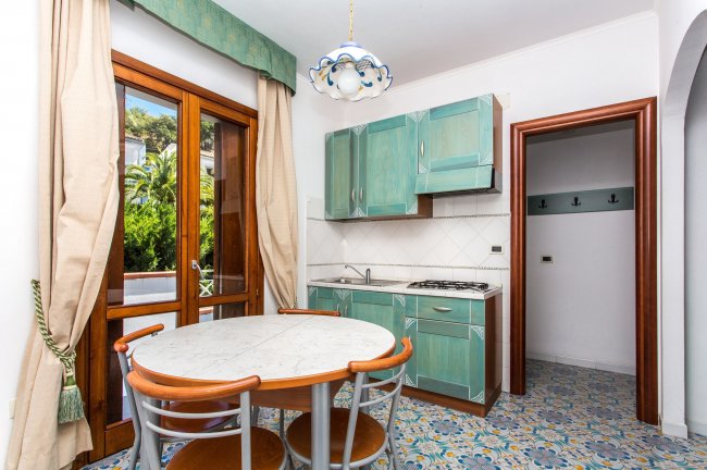 Cucina con tavolo rotondo e sedie, tende beige.