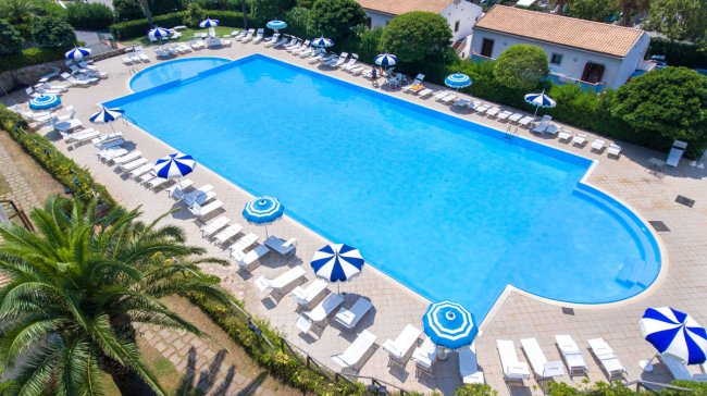 Piscina rettangolare con lettini e ombrelloni blu e bianchi tutt'intorno.