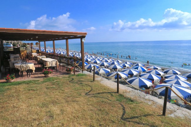 Spiaggia con ombrelloni blu e bianchi.