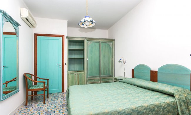 Camera con letto verde, armadio e porta turchese.
