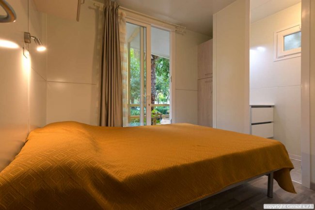 Camera da letto con un letto matrimoniale e una finestra sul giardino.