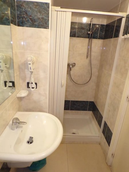 Bagno con doccia e lavandino bianchi.
