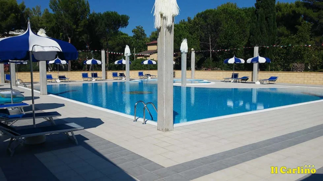 Piscina contornata da lettini e ombrelloni.