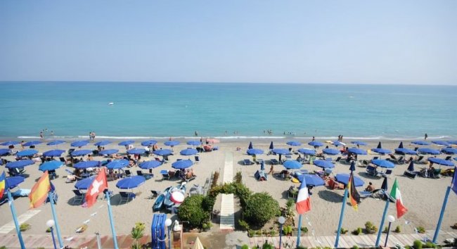 Spiaggia con ombrelloni blu e mare calmo.