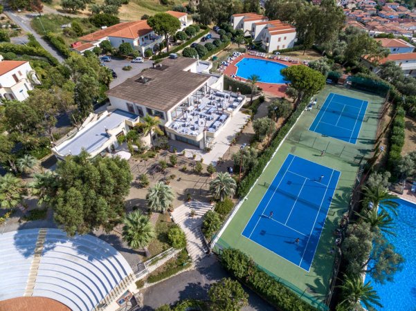 Vista dall'alto su un complesso con campi da tennis, piscine e edifici.