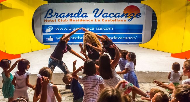 Un gruppo di bambini partecipa a un'attività di animazione su un palco all'aperto.