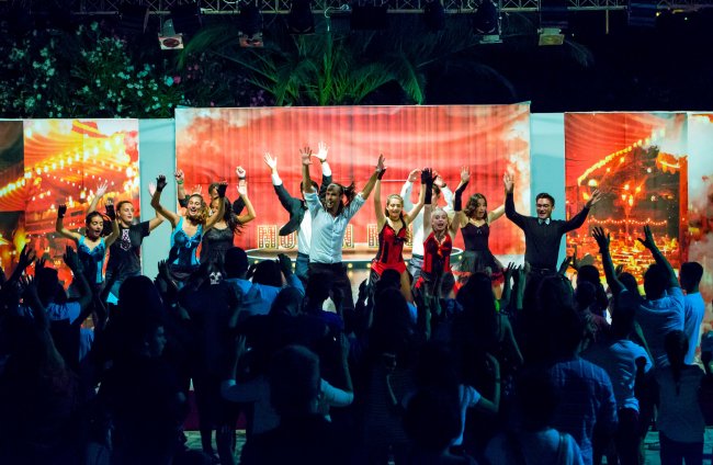 Spettacolo colorato con gruppo di persone che ballano sul palco.