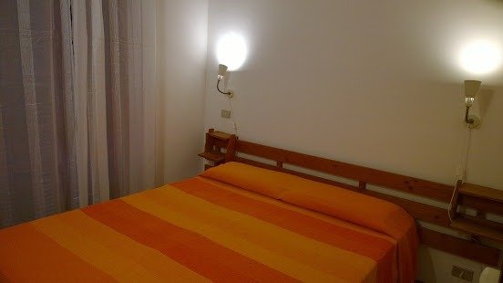 Camera con letto matrimoniale e luci da parete.