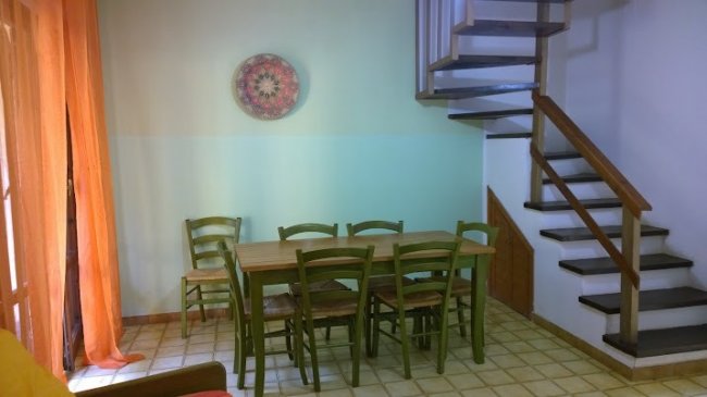 Tavolo e sedie in soggiorno, scala a chiocciola accanto.
