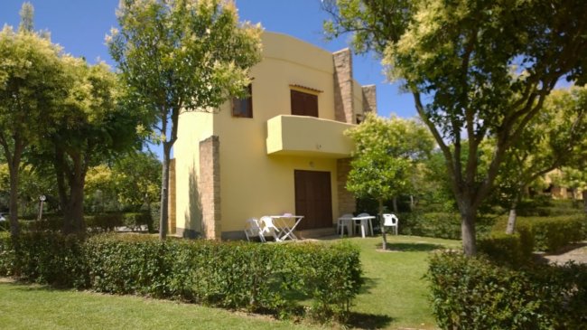 Casa gialla con giardino e alberi circostanti.