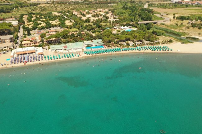 Acqua limpida e complesso turistico lungo la spiaggia.