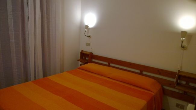 Camera da letto con letto matrimoniale arancione e due lampade a parete.