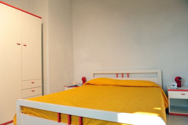 Camera con letto matrimoniale e armadio bianco e rosso.