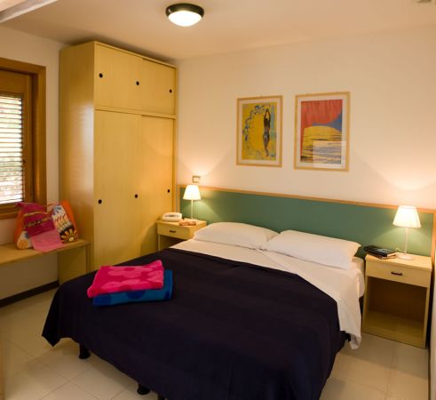 Camera con letto matrimoniale, armadio, comodini e quadri alle pareti.