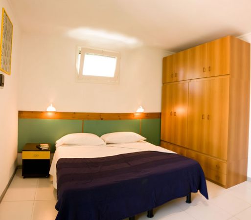 Una camera da letto con letto matrimoniale, armadio in legno e due lampade da parete.