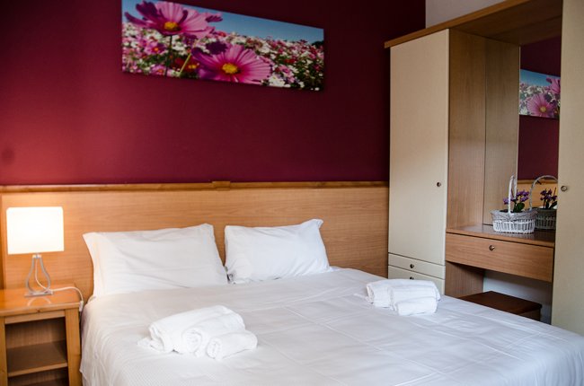 Camera da letto con pareti rosse, letto matrimoniale e lampada da comodino.