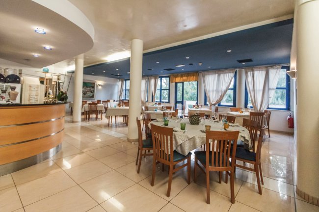Ristorante elegante con tavoli apparecchiati e sedie in legno.