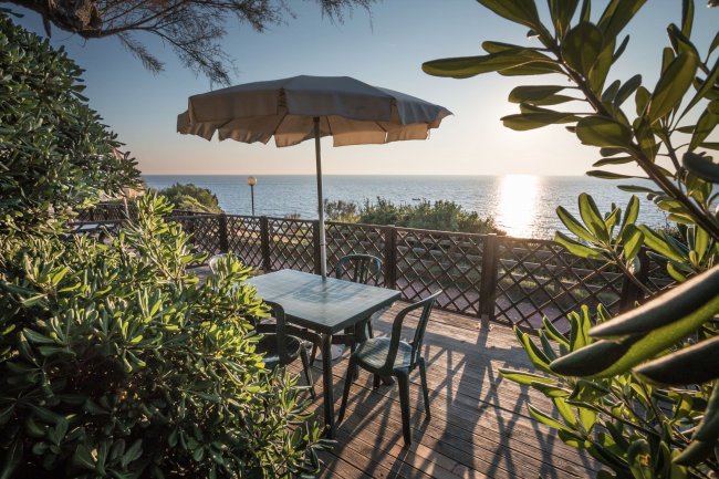Tavolo da esterni con ombrellone affacciato sul mare al tramonto.
