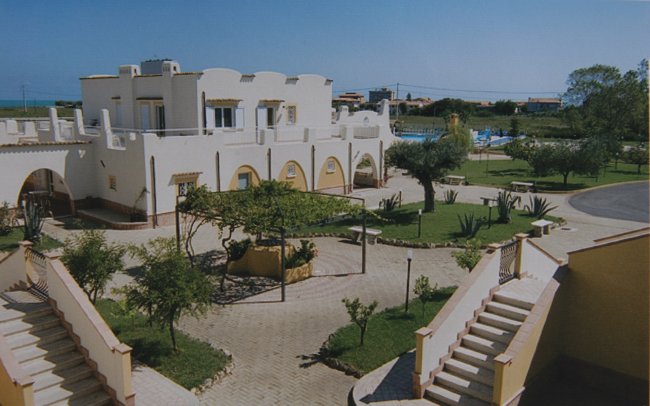 Edificio bianco con giardino, scale e piscina sullo sfondo.