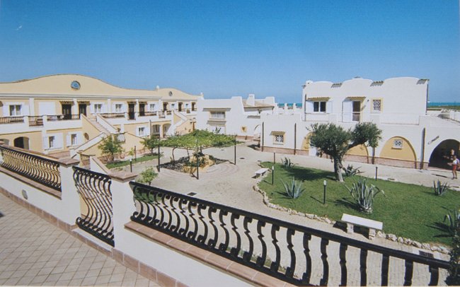 Complesso residenziale mediterraneo con cortile alberato.