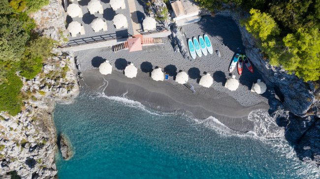 Spiaggia con ombrelloni, kayak e mare blu.