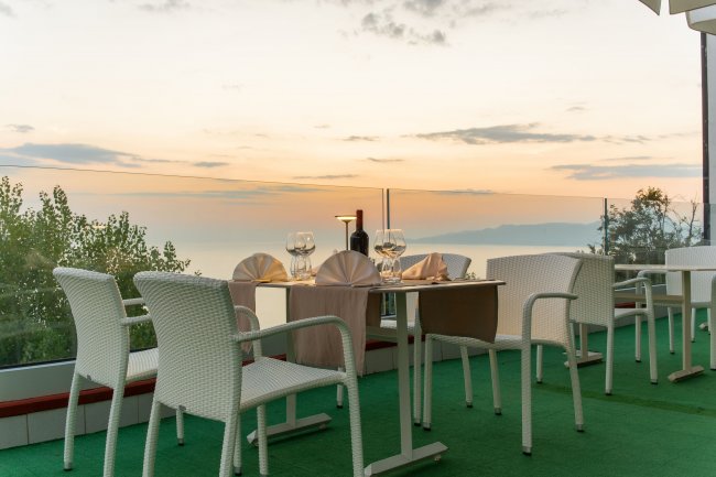 Tavolo apparecchiato al tramonto con sedie bianche e vista panoramica.