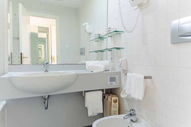 Un bagno moderno con lavabo, specchio grande e bidet.