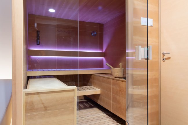 Una sauna in legno con luci soffuse e secchio.