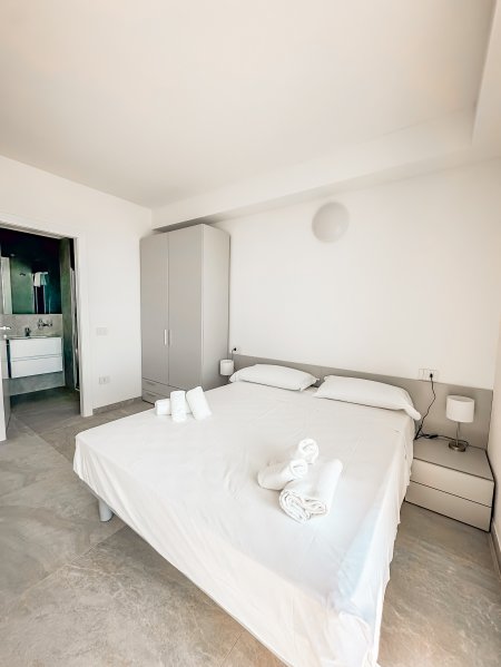 Camera da letto con letto matrimoniale, due comodini, armadio e bagno sullo sfondo.