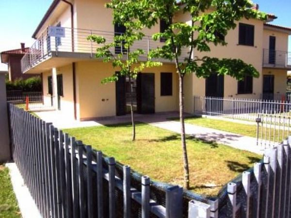 Casa moderna con giardino recintato e piccolo albero.