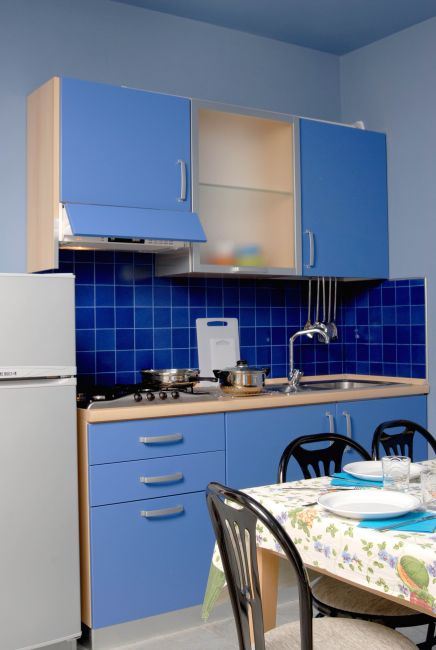 Cucina con mobili blu, piastrelle blu e tavolo apparecchiato.