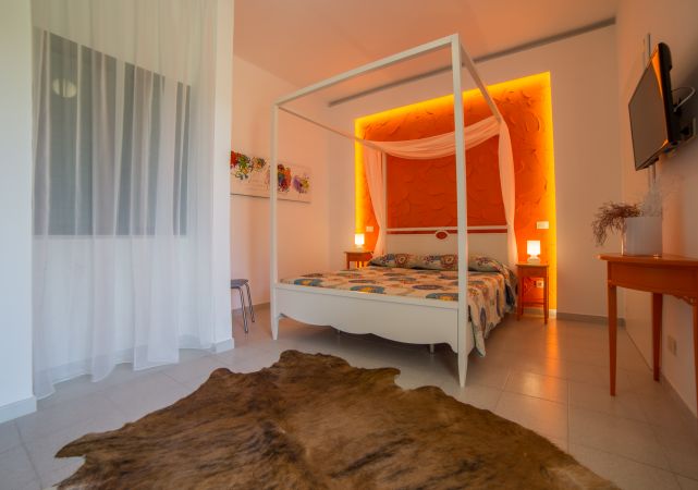Camera da letto con letto a baldacchino bianco, parete arancione illuminata e tappeto marrone.