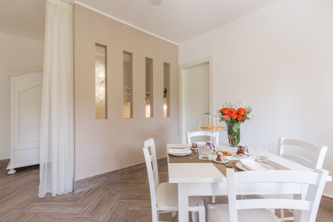 Sala da pranzo moderna con tavolo bianco e fiori arancioni.